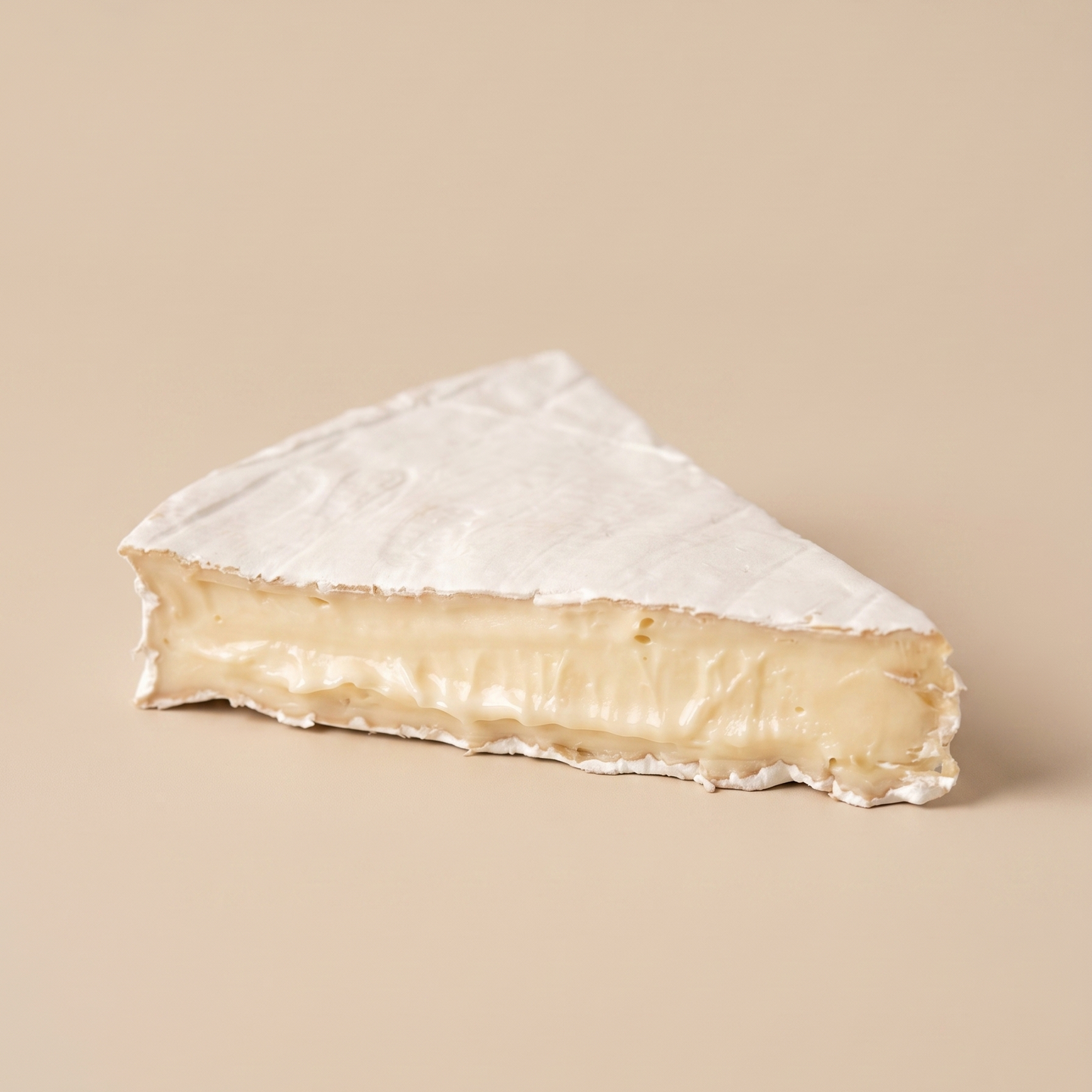 Queso Brie artesanal sobre fondo beige.