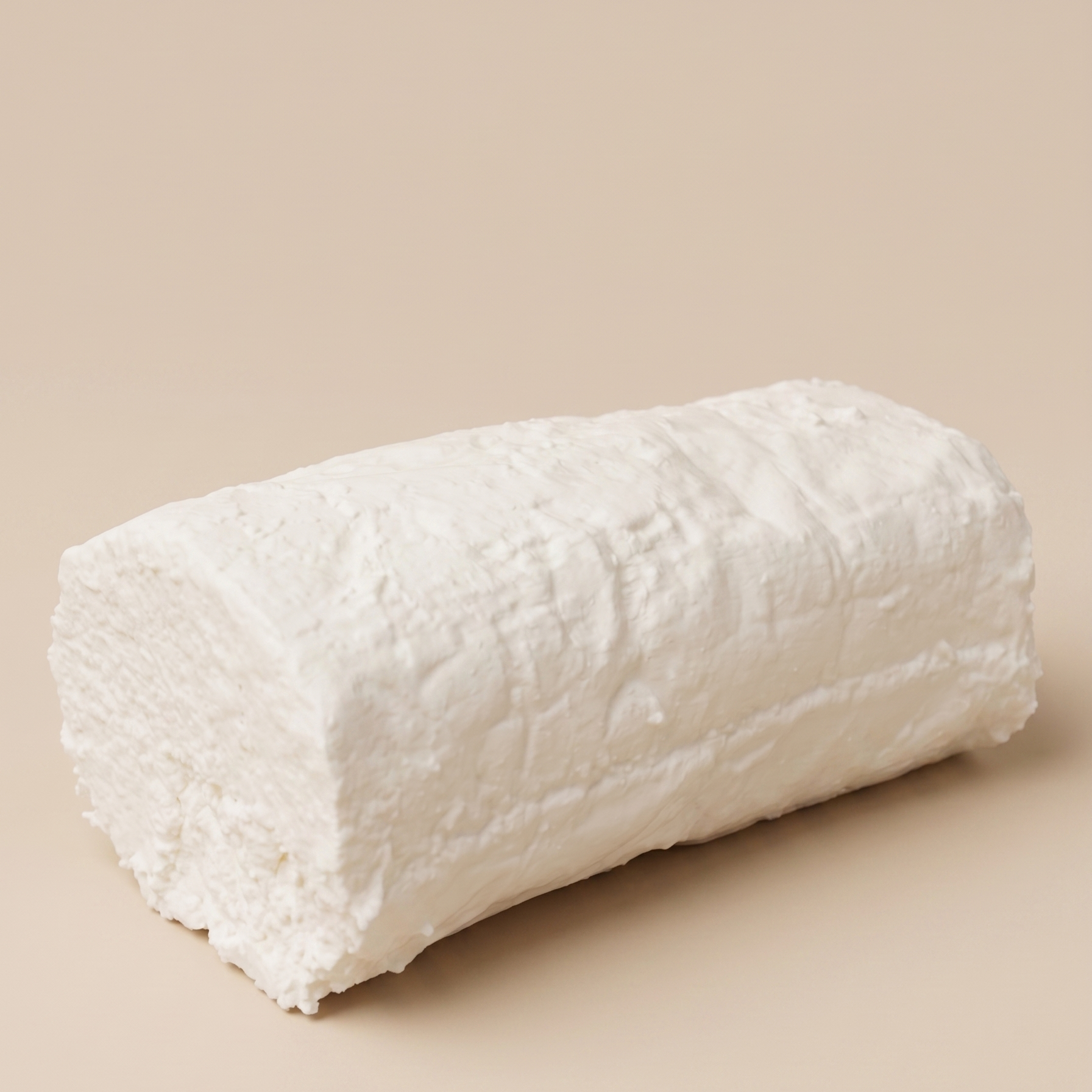 Queso fresco de cabra artesanal sobre fondo beige.